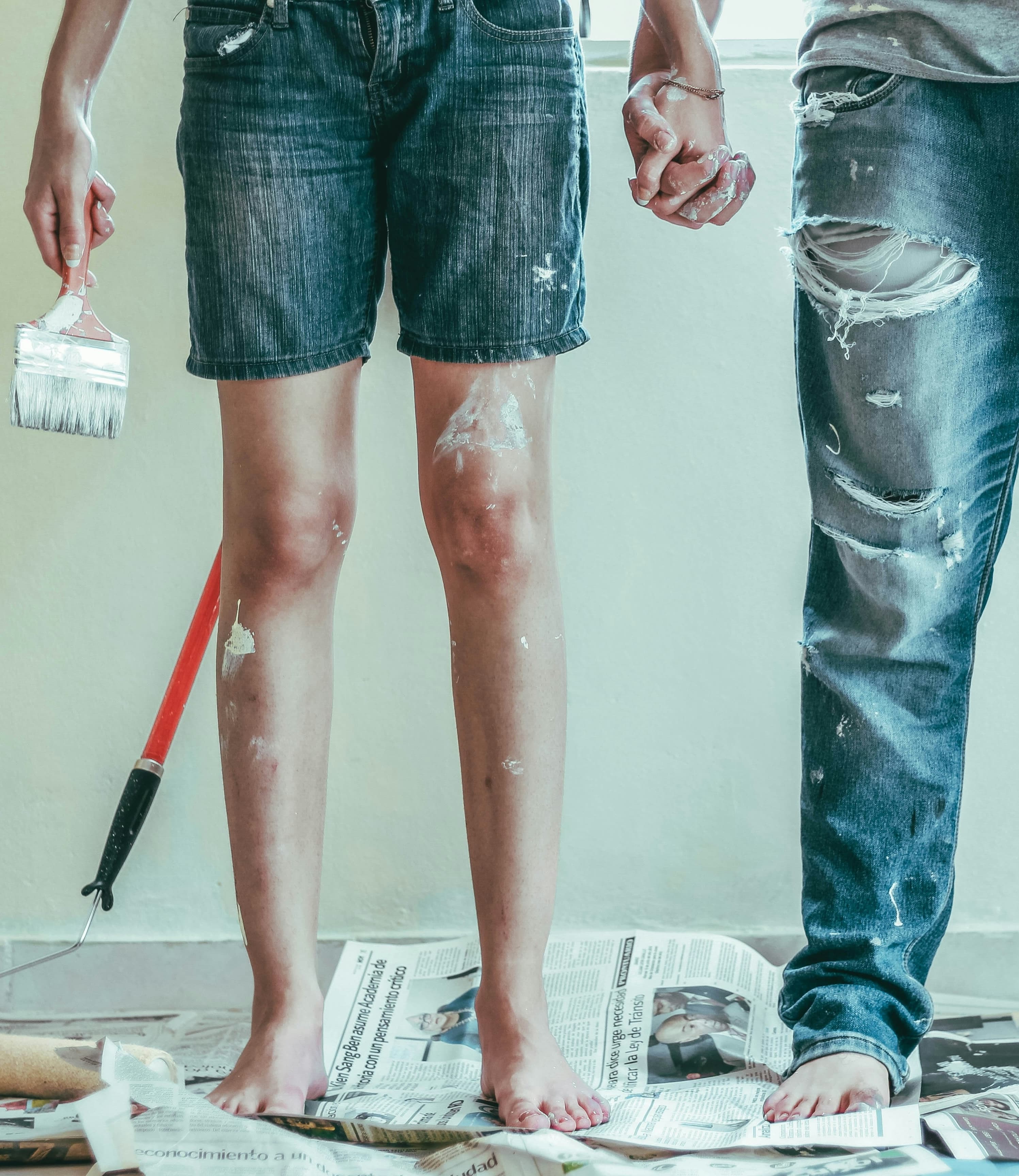 Two people painting a room together, holding hands